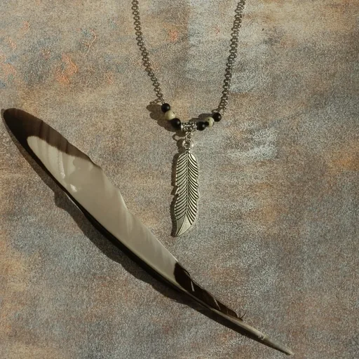 Collier composé d'une chaîne fine ornée d'une breloque en forme de plume et de p